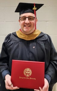 Youngstown State MBA graduate Ricky Neal wearing a black suit and red shirt in a professional photo