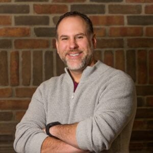 Youngstown State MBA graduate Aaron Tervo smiling with arms crossed in a professional photo