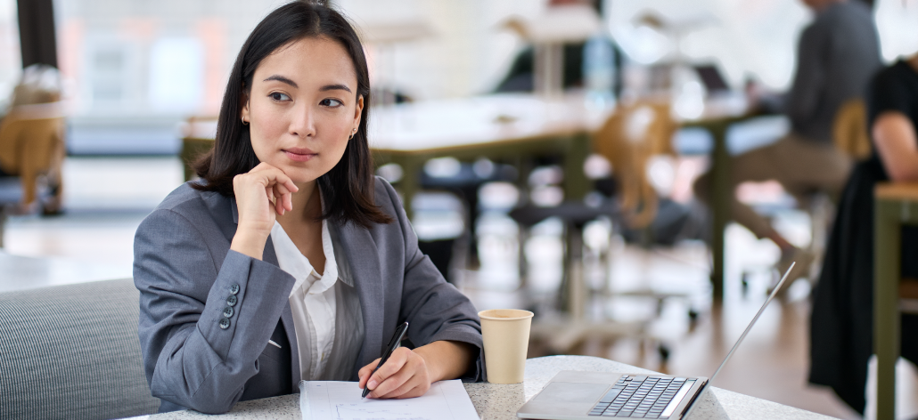 A business woman sits at a table thinking.