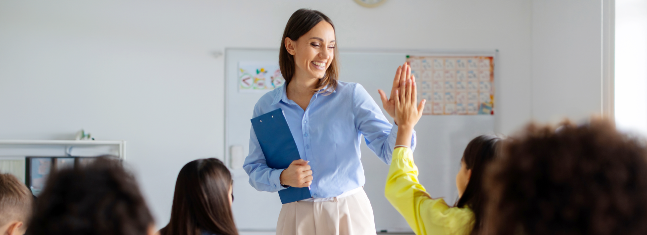 Teacher gives student a high-five in the classroom